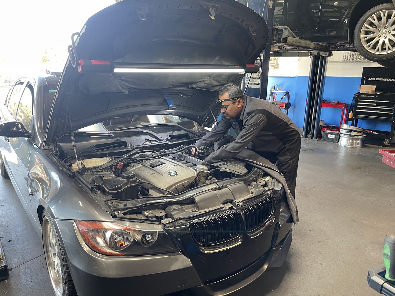 A MOTEC technician working under the hood of a BMW in the shop